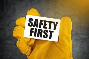 38645450 - safety first on business card, male hand in yellow leather construction working protective gloves holding card with rounded corners.