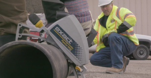 Safety survey being done on a construction site. A safety manager is watching an employee cut a steel pipe