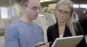 Two employers doing a safety walkthrough of their workplace facility. Both are looking at a checklist and discussing the contents of the checklist. 